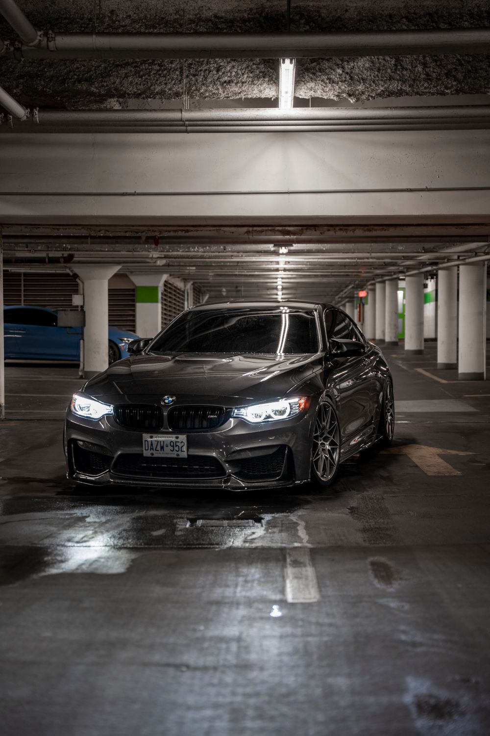 Karanlık bir kapalı otoparkta farları yanık duran gri bir BMW